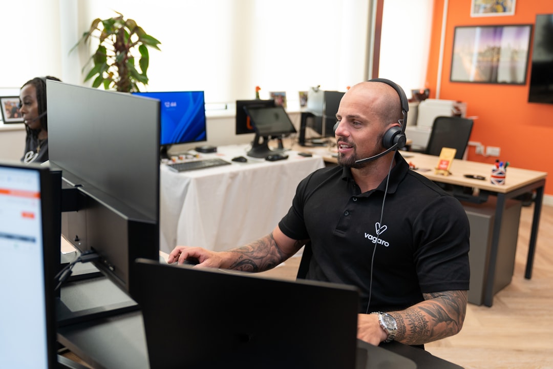 services-01 A customer support representative at Vagaro is assisting a client through a headset, offering support in an office.